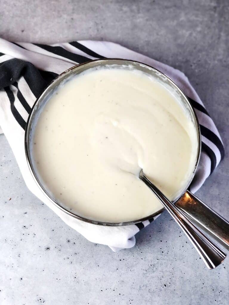 Bechamel sauce in a saucepan with a serving spoon.