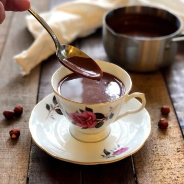 Italian hot chocolate in a cup on a wood board with a spoon dipped in it