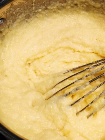 creamy instant polenta in a pot with a whisk