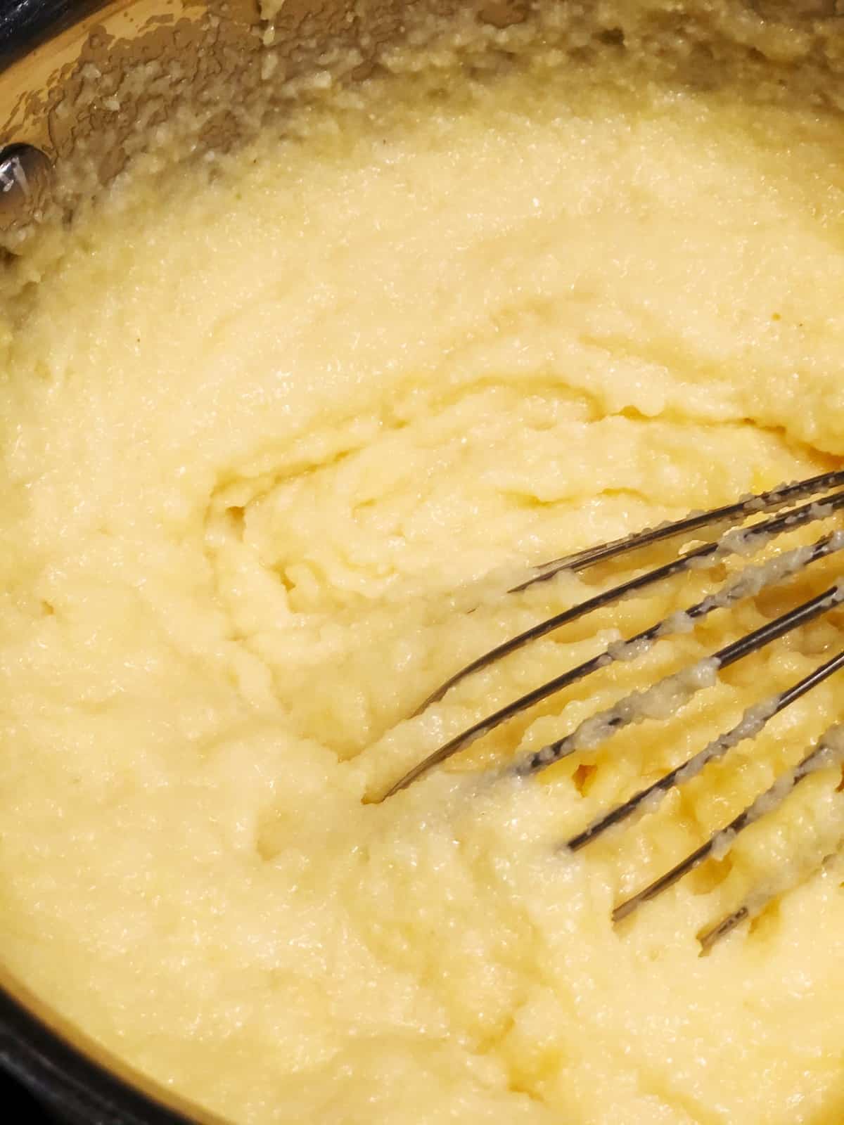 creamy instant polenta in a pot with a whisk