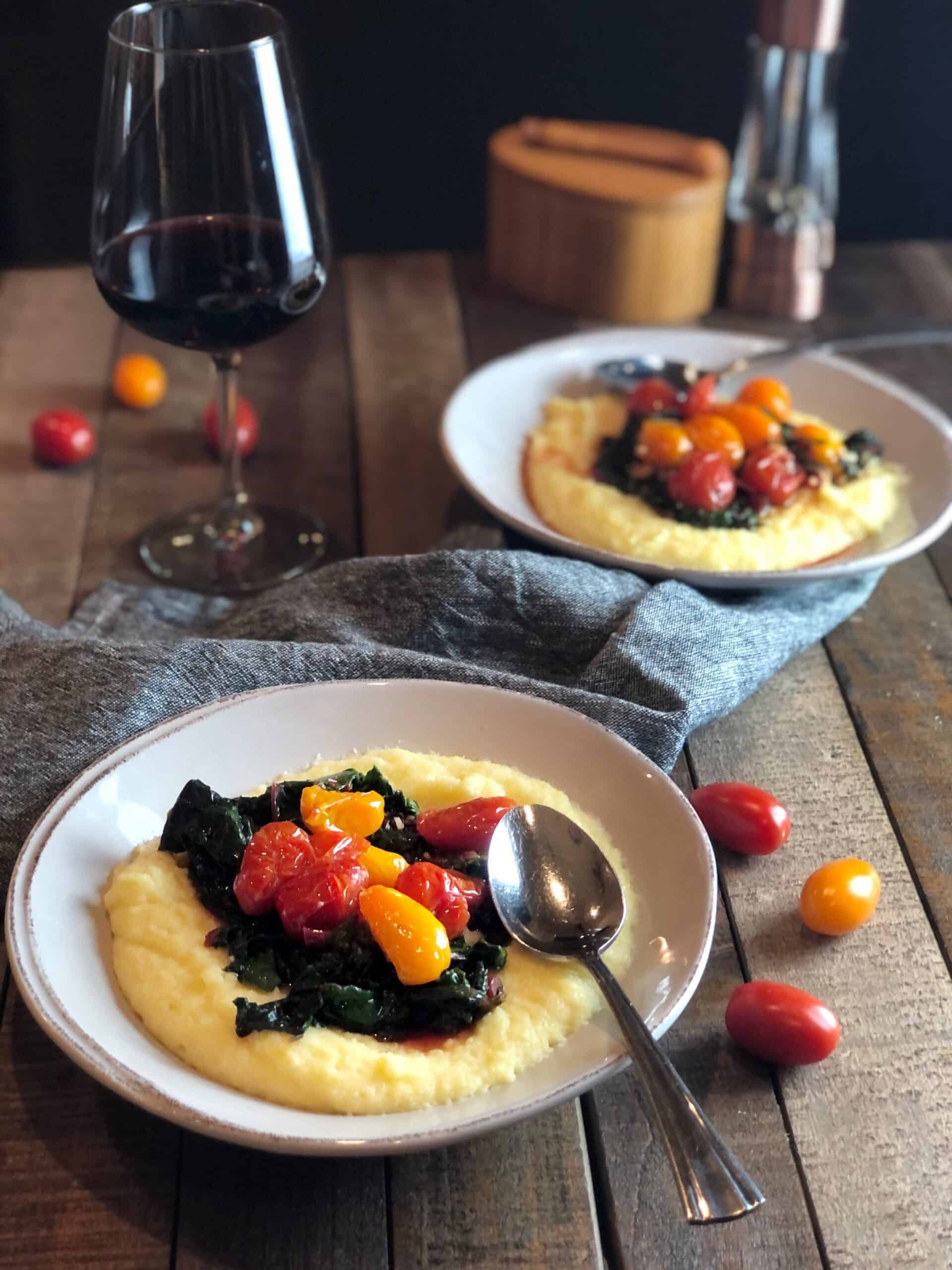 creamy polenta with tomatoes in two bowls with a glass of wine