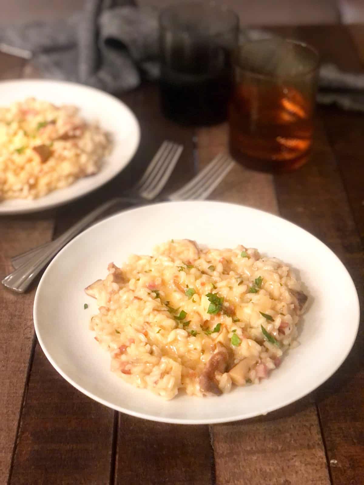 Two bowls of pancetta risotto on a wood table