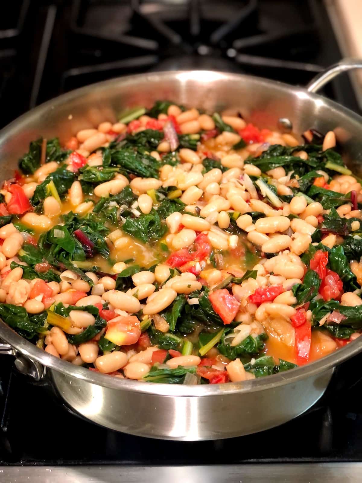 white beans and chard in a saute pan on the stove