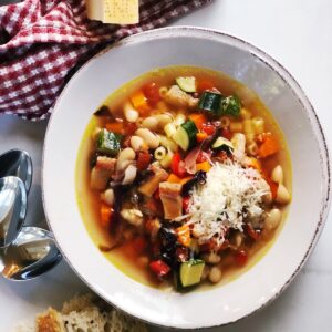 Italian minestrone soup and pasta in a bowl with Parmesan on top.