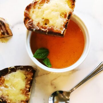 passata tomato soup in a small bowl with garlic bread on the side.