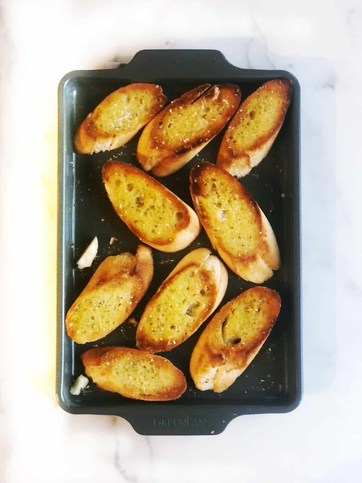 Slice baguette bread on a sheet pan.