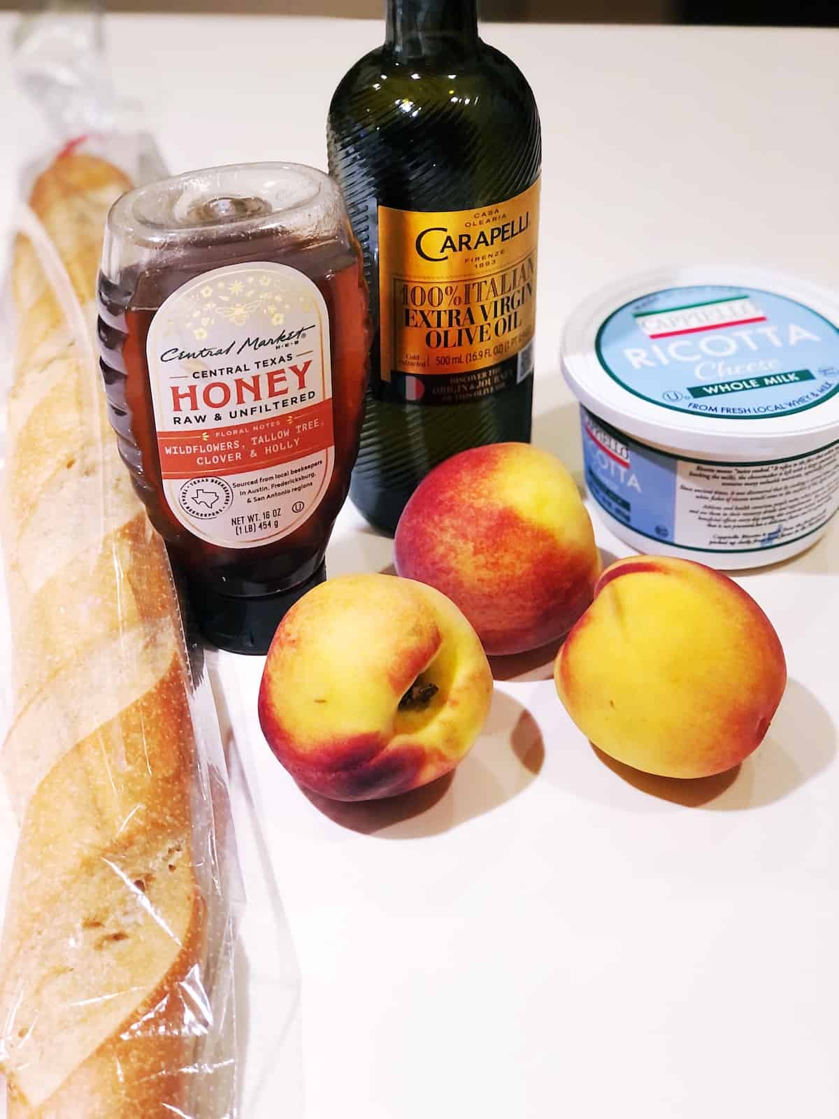 Ingredients for peach ricotta on a white counter.