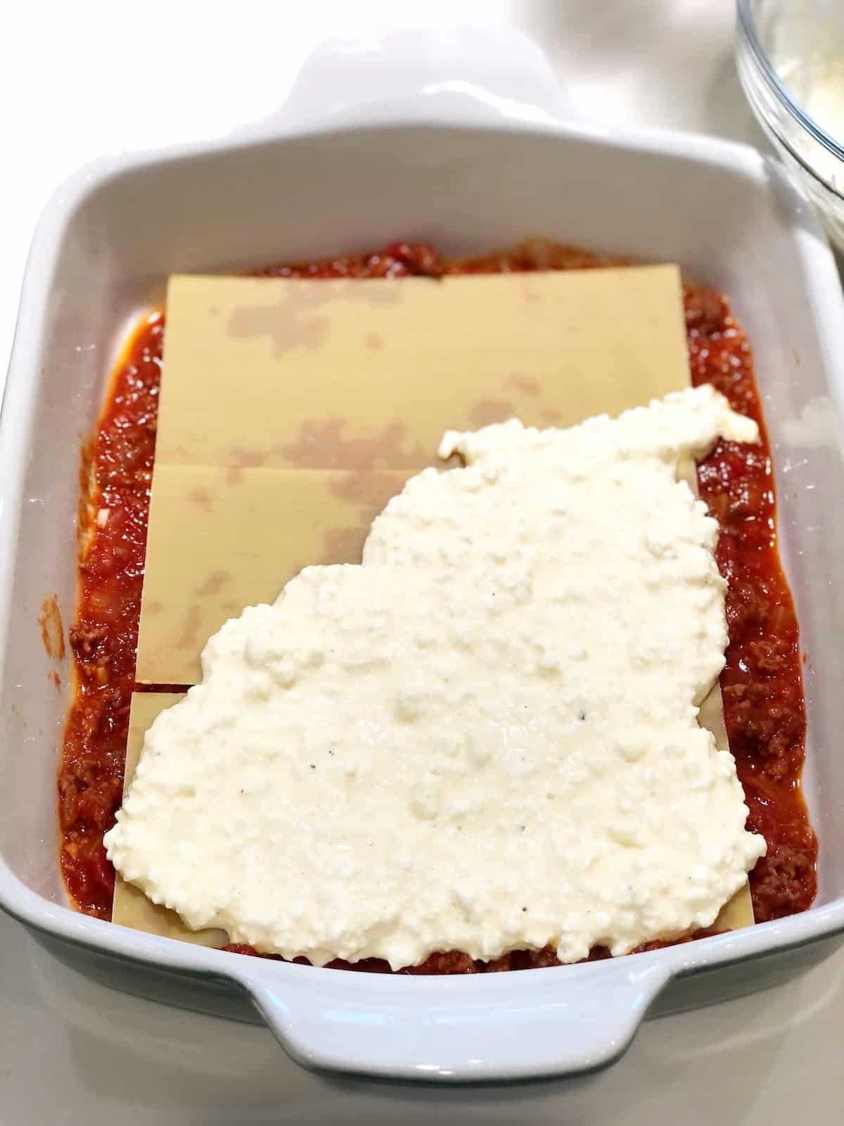 How to make Italian American Lasagna - adding lasagna noodles, meat sauce and cheese layers.