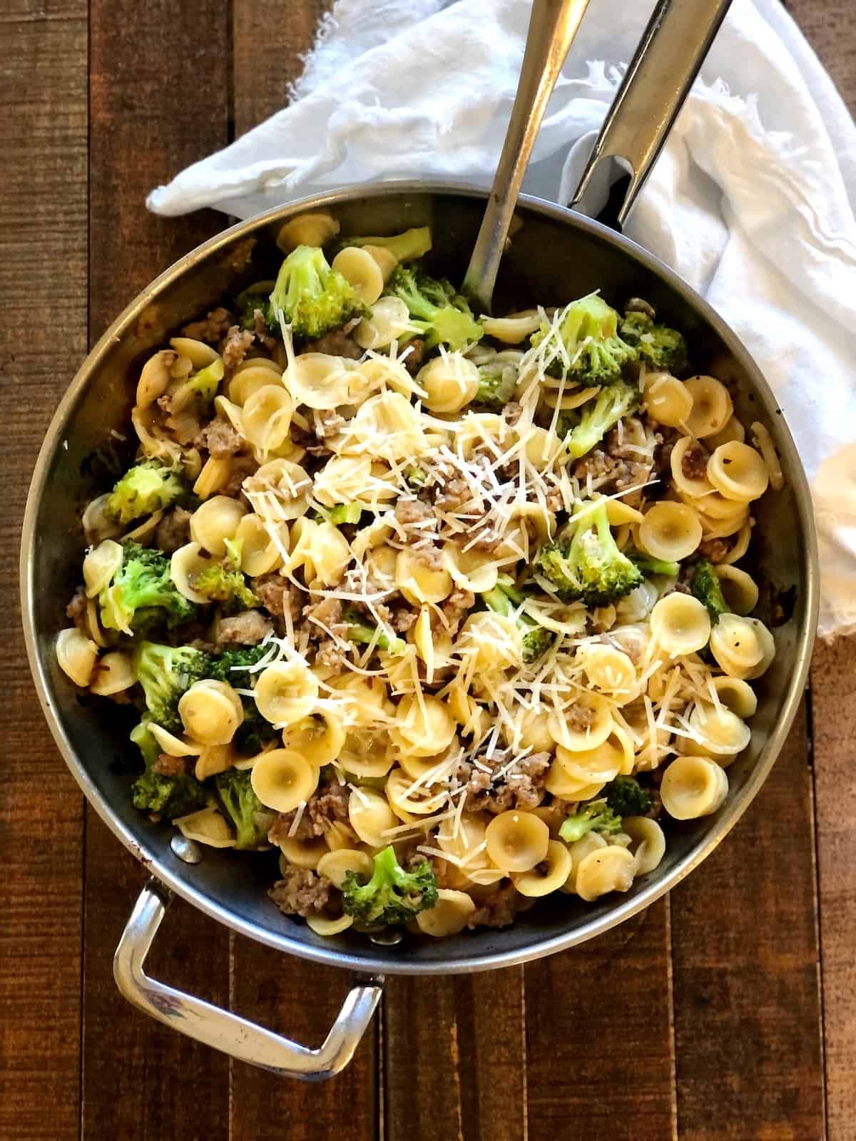 sausage broccolini pasta in a pan on a wood counter.