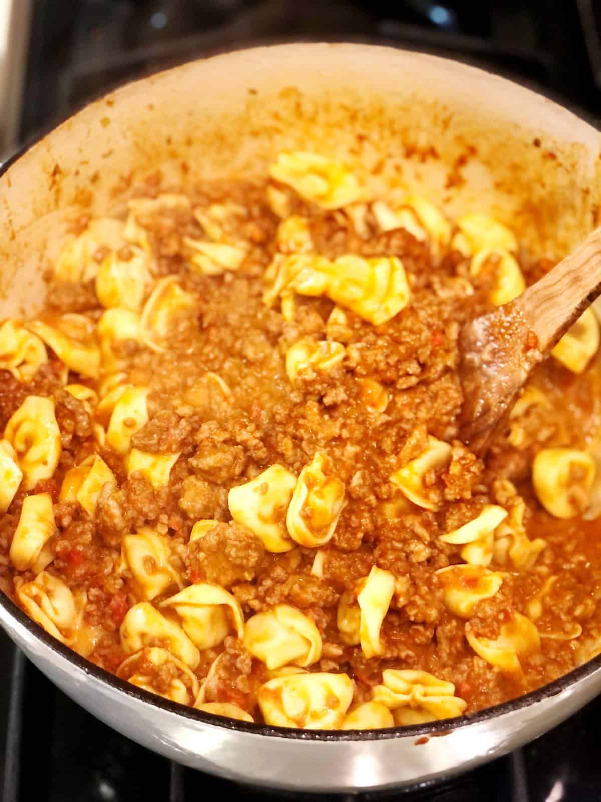 Mixing the creamy tortellini Bolognese.