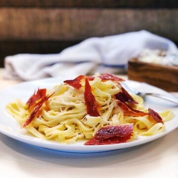 fettuccine with crispy prosciutto on a plate.