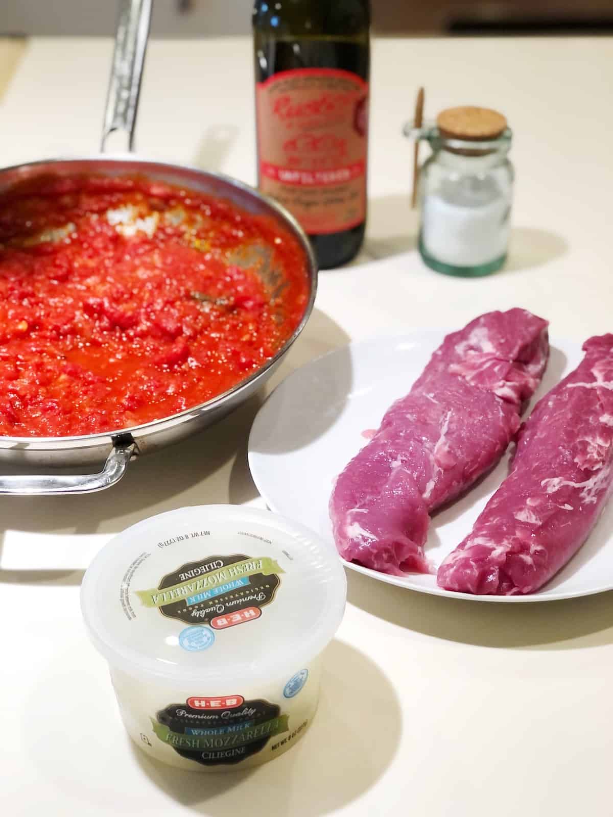 ingredients for pork tenderloin in tomato sauce on the counter.