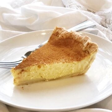 Ricotta pie slice on a plate with cinnamon on top.
