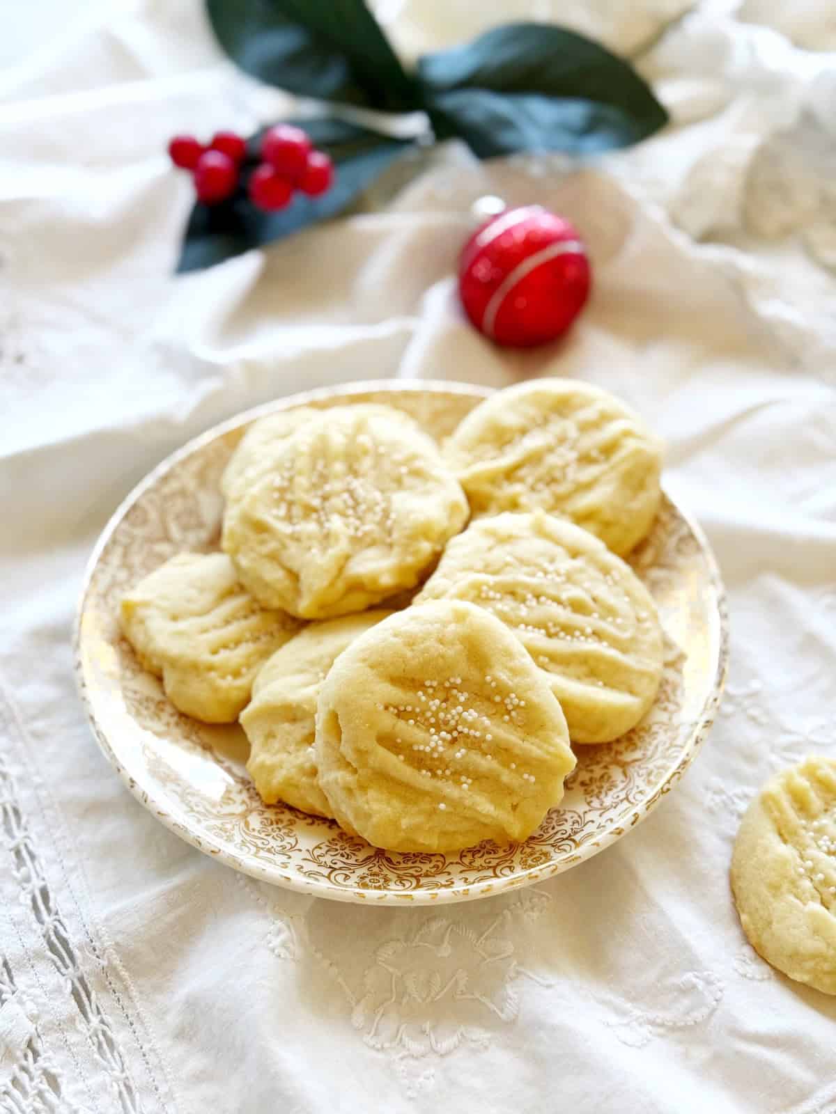 Whipped Italian Anise Shortbread Cookies on a plate with holiday decorations in background.