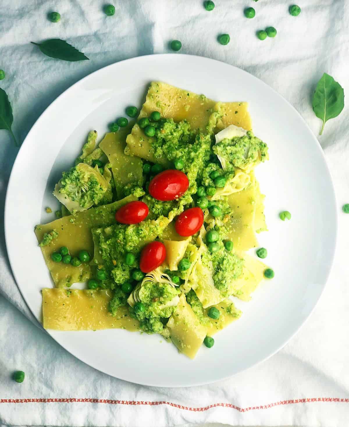 Pasta, pesto and peas tossed together on a white plate.