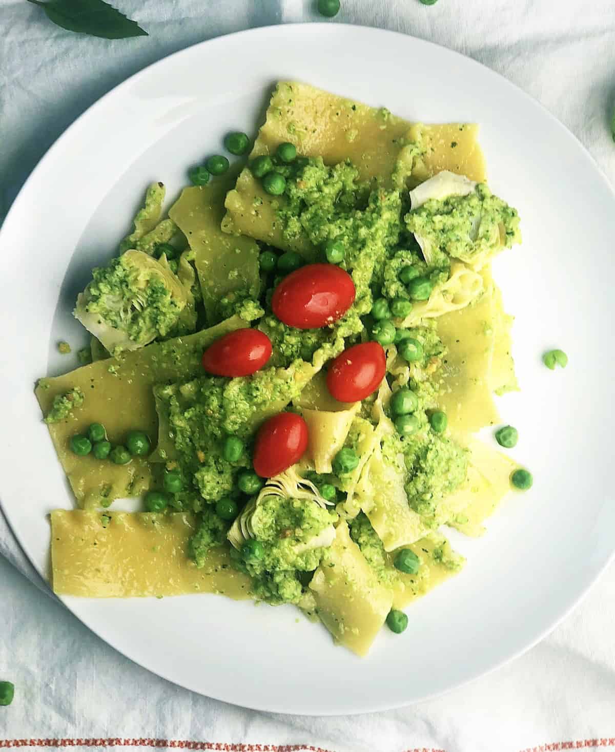 Pasta with pesto and peas on a large plate.