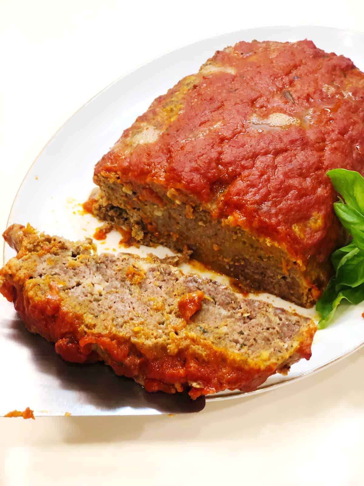 Italian meatloaf baked and sliced on a serving plate.