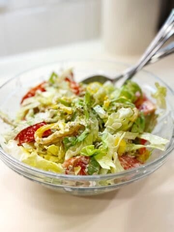 Italian salad in a bowl on the counter with a serving spoon.