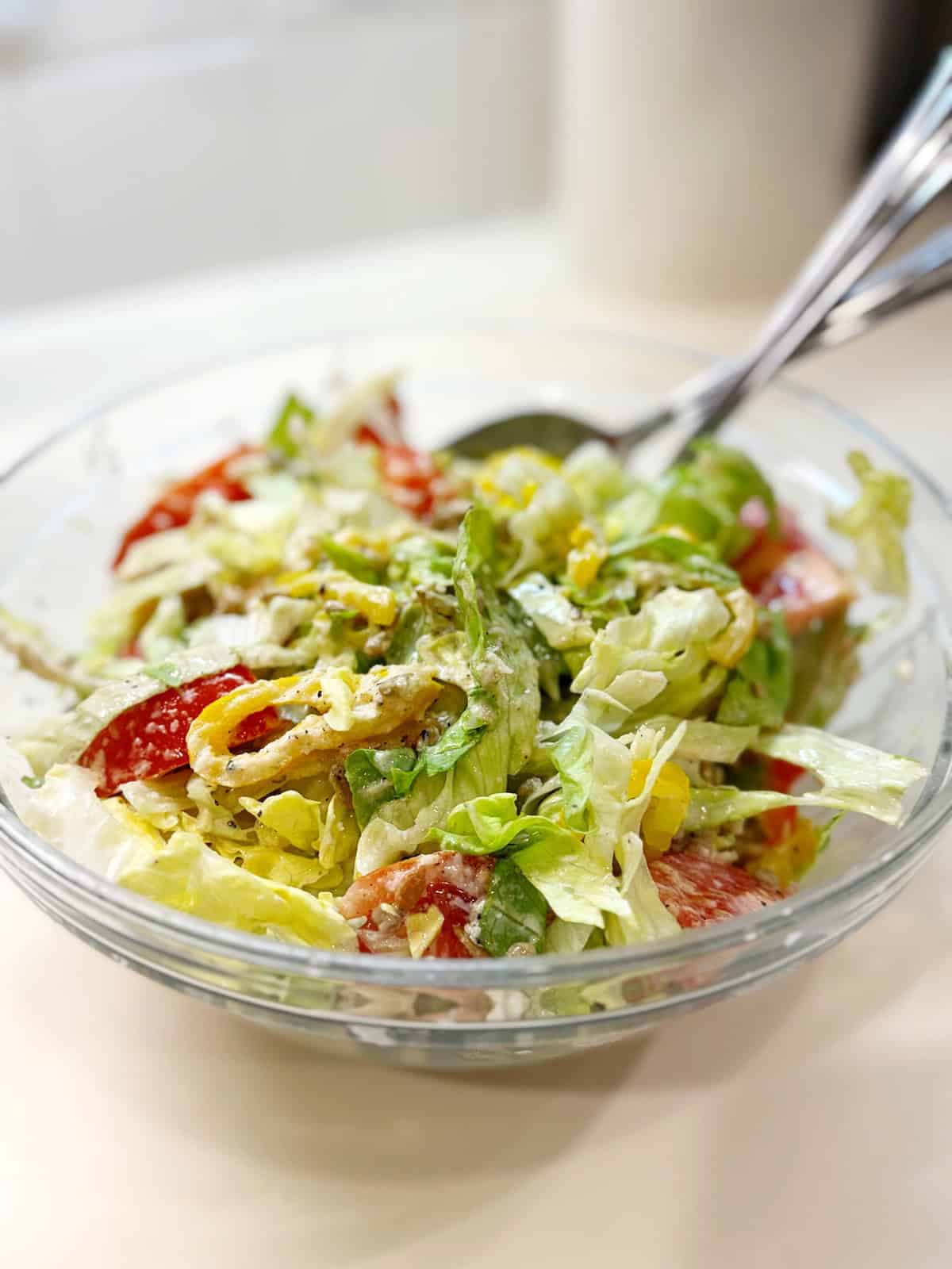Italian salad in a bowl on the counter with a serving spoon.