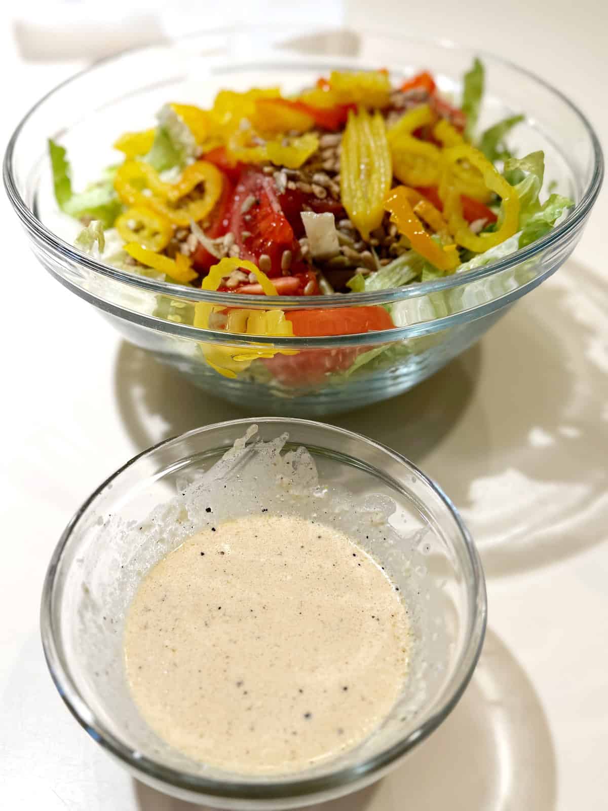 Creamy Parmesan dressing next to the bowl of salad.