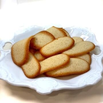 Italian butter cookies (lingue di gatto) on a plate.