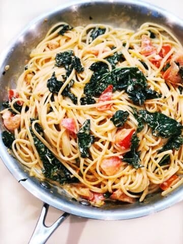 Creamy Spaghetti With Kale And Tomatoes in a saute pan.