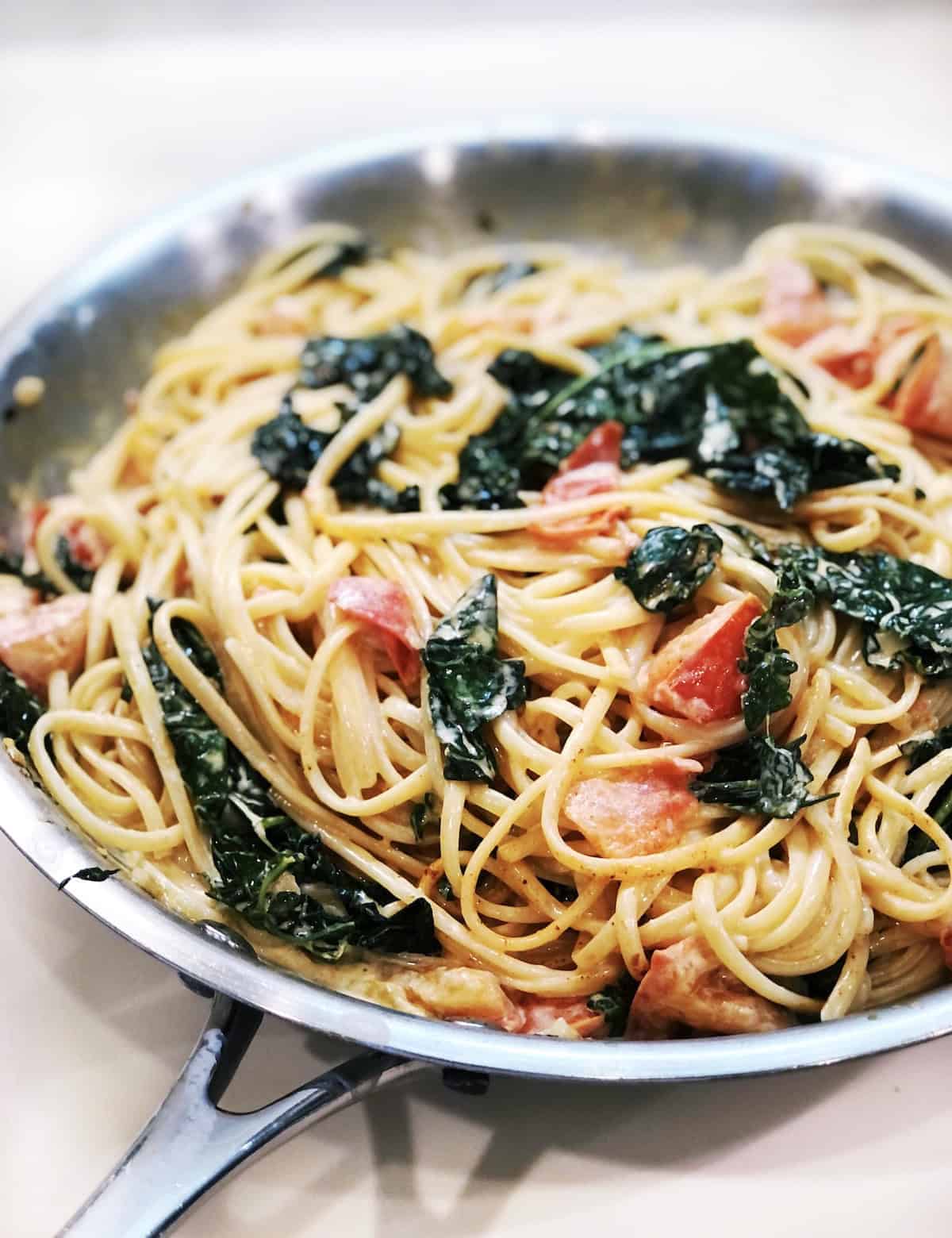 Creamy Spaghetti With Kale And Tomatoes closeup in a large pan.
