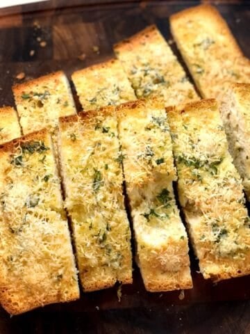 Slices of olive oil garlic ciabatta bread on a cutting board.
