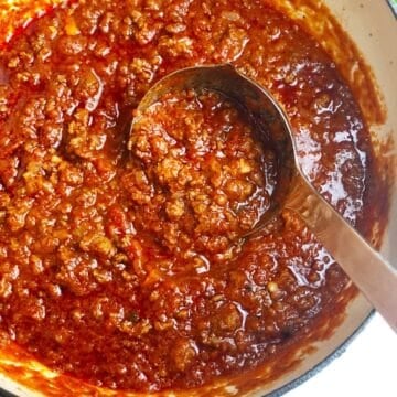 Italian meat sauce in a a large pot with a ladle.
