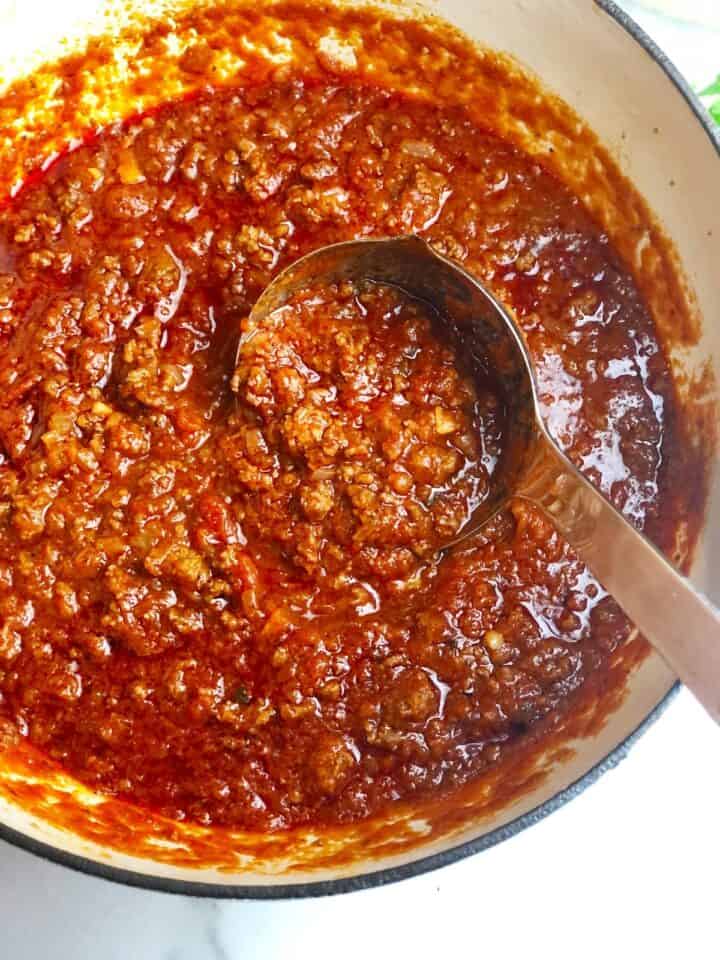 Italian meat sauce in a a large pot with a ladle.