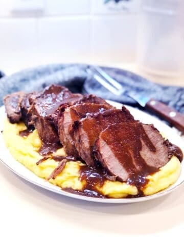 Brasato al Barolo on a bed of polenta with a thick sauce poured over the top.