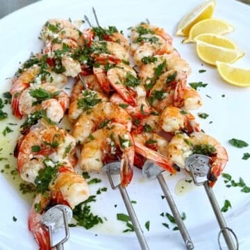 Italian grilled shrimp on a plate with lemons.